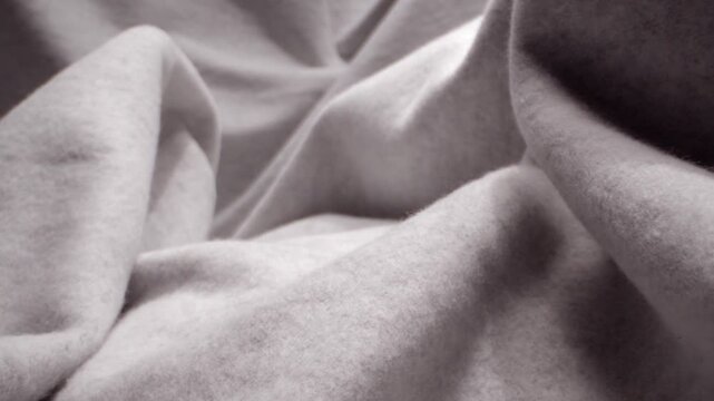 Macro view of gray soft fleece fabric texture with deep folds and gentle motion.