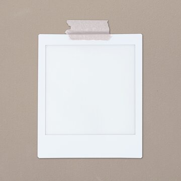 Blank polaroid photo frame taped on beige wall mockup