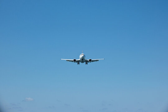 Front View of Passenger Airplane Flying Directly Towards Viewer in Blue Sky