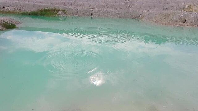 Scenic view of a turquoise quarry lake surrounded by white kaolin clay formations and exposed mineral-rich terrain.