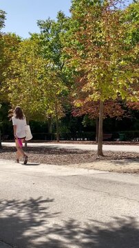Mujer de paseo en parque con ropa deportiva, botella t&eacute;rmica rosa y &aacute;rboles de fondo chica paseando tranquila 
