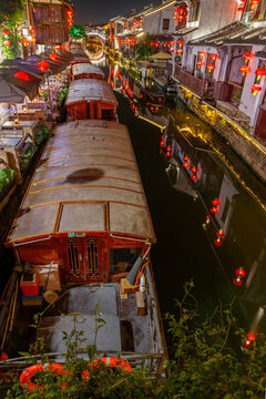 Suzhou, China, the historic Shantang Street featuring wooden tour boats, glowing red lanterns and stone bridge reflections