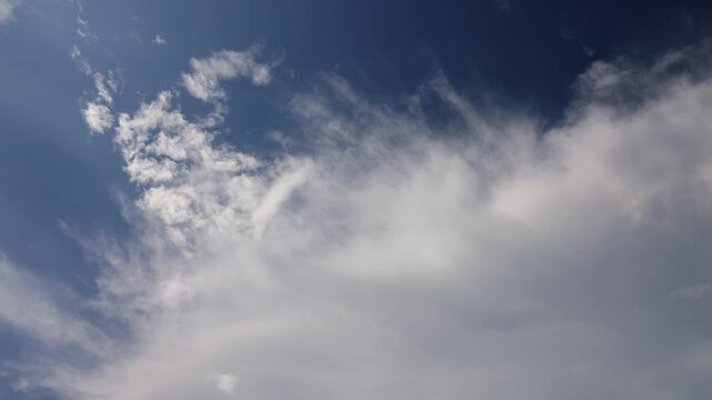 Clouds moving across a blue sky in a time-lapse, showing changing weather patterns, atmospheric movement, sunlight and natural sky conditions for weather and environmental content.
