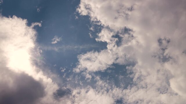 Clouds moving across a blue sky in a time-lapse, showing changing weather patterns, atmospheric movement, sunlight and natural sky conditions for weather and environmental content.