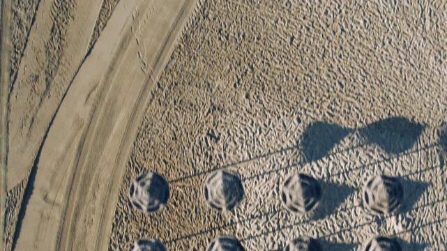 Aerial top down view of straw umbrellas on sandy beach