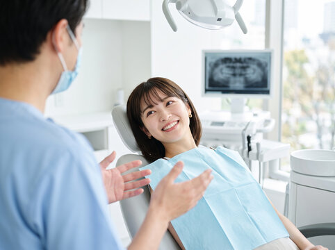 歯科医院で医師の説明を笑顔で聞く女性