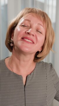 Close up of woman with short blonde hair wearing black and white houndstooth patterned blazer silver necklace and pink stone earrings. subject head moves slightly revealing details of her
