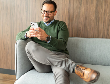 Mature man communicating and interacting with a smartphone, managing business tasks, legal matters, or financial accounting, sitting comfortably on a modern seat