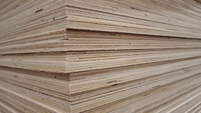 Stacked plywood sheets in close view at a warehouse. Building material, woodworking supply, construction industry, manufacturing stock, industrial texture.