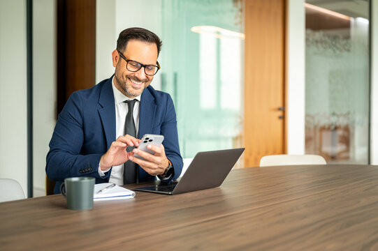 Professional businessman smiling, interacting with digital device in office, managing communications, finances, and legal matters with modern technology