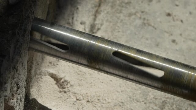 Precision boring bit punches deep into concrete block during construction. Macro shot.