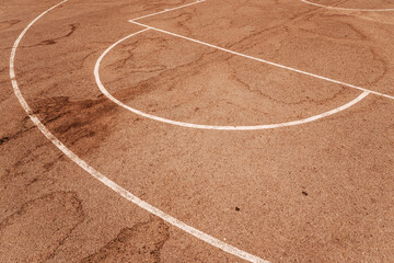 High angle view of white painted game lines on a reddish-brown asphalt outdoor basketball court...