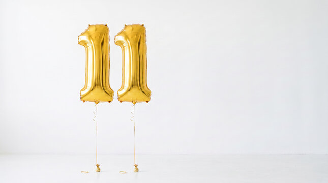 Gold number eleven foil balloons floating against a clean white background with copy space, ideal for 11th birthday, anniversary, milestone and celebration concepts.