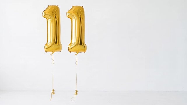 Gold number eleven foil balloons floating against a clean white background with copy space, ideal for 11th birthday, anniversary, milestone and celebration concepts.