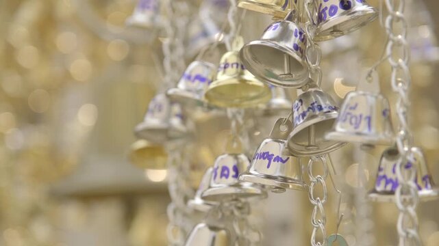 Selective focus on the group of golden and silver bell strings inside the Buddhist temple.