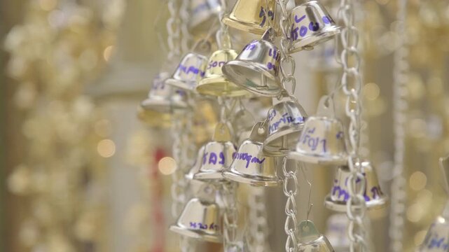 Close up of the group of golden and silver bell strings inside the buddhist temple.