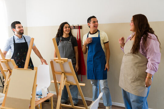 Adults participating in an art class, socializing and painting on easels. Expressing creativity and enjoying a hobby