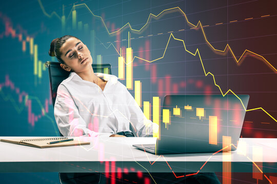 Exhausted businesswoman sleeping at an office desk beside a laptop as volatile financial charts signal overnight trading crisis and corporate market stress.