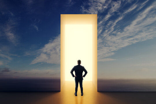 Businessman Seen From Behind Standing Before a Bright Open Door to a New Life, Hope, Opportunity, and Creative Business Direction.