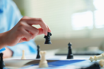 Business strategist moving a black chess knight above performance reports with a defeated piece in the foreground, competitive disruption, corporate strategy, executive leadership, market displacement © Joi_studio