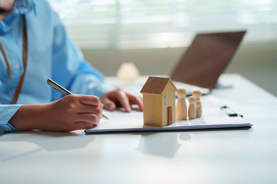 Estate planning attorney drafting a living trust and will on a clipboard beside wooden family figurines and a house model, generational wealth transfer, legal inheritance, and family asset protection
