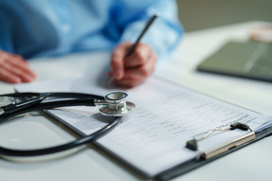 Healthcare administrator reviewing an insurance policy schedule with a stethoscope on a clipboard, health insurance coverage, medical underwriting, prior authorization, patient claims processing