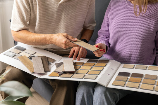Couple choosing flooring and furniture materials from wood samples for home renovation. Interior design