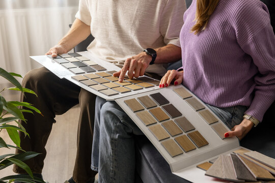 Couple choosing flooring and furniture materials from wood samples for home renovation. Interior design