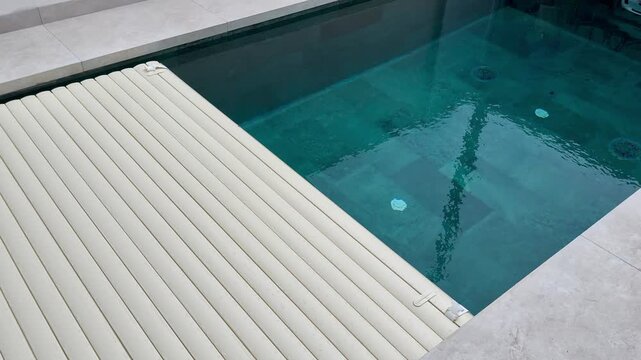 Automatic pool cover opening over a modern swimming pool