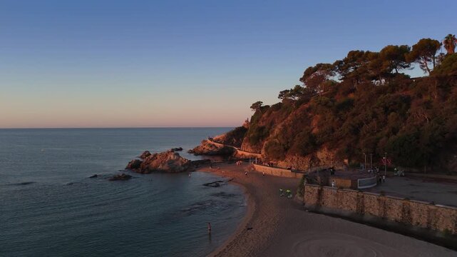 Aerial view taken from a drone of the coast of Lloret de Mar, Costa Brava, Spain, early in the morning at sunrise - the sea, beach and coastal cliffs of the city bay