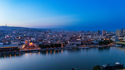 Obraz premium Panoramic skyline of Bratislava along Danube river during blue hour. Deep sky extends over illuminated embankments and city buildings.