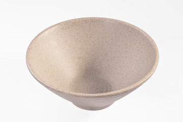 Empty ceramic bowl with speckled beige glaze and ribbed exterior on white background