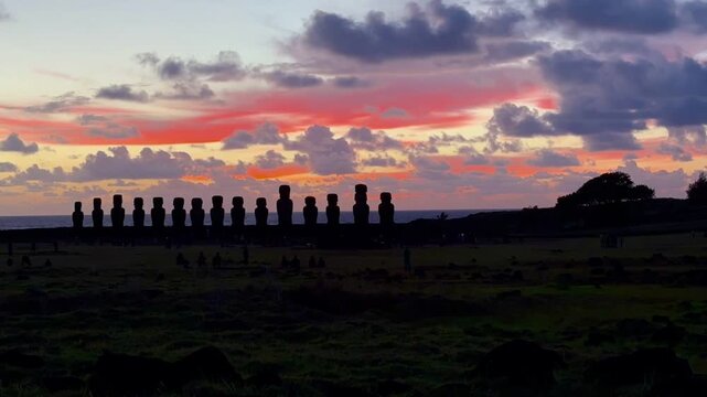 Sunrise over Ahu Tongariki on Easter Island, Chile, with the iconic Moai statues silhouetted against a colorful sky in a time-lapse.