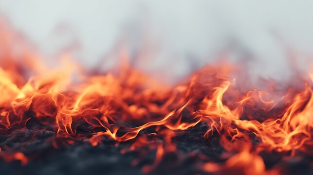 Close-up image of bright orange and red flames burning intensely with smoke rising above a dark background.