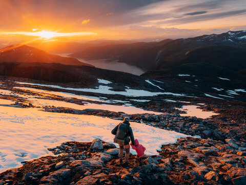 Father and daughter mountaineering in Norway hiking sunset mountains together, family travel adventure lifestyle active vacation backpacking outdoor child exploring nature with dad bonding moments