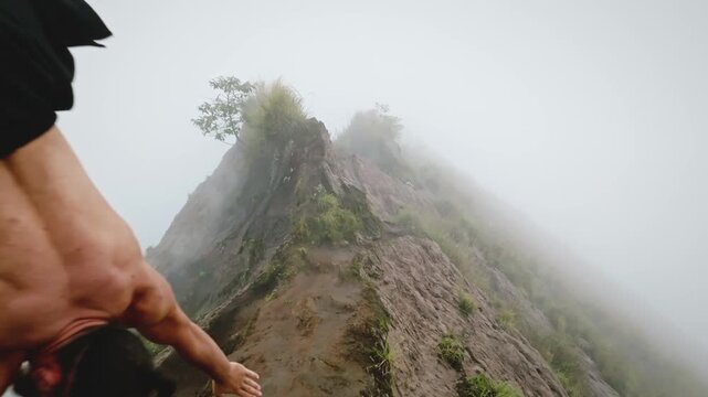 Man balancing on hands performing a handstand on a foggy mountain ridge, showcasing strength, balance, and adventurous fitness in a challenging outdoor environment
