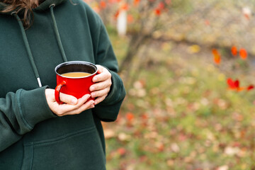 Obraz premium Close up of hands holding a red enamel mug filled with a hot drink