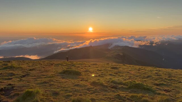 Dinamic footage of hikers with headlamps trekking along a mountain ridge at dusk, surrounded by layered forested peaks and a dramatic twilight landscape.