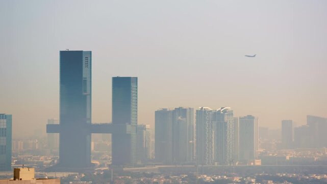 Airplane flies over the futuristic One Zaabeel towers and modern skyscrapers of Dubai shrouded in morning desert haze