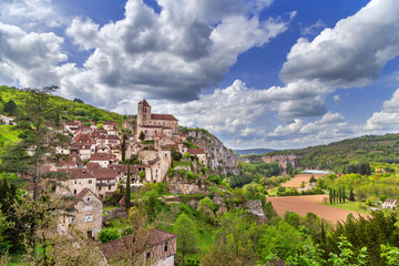 Fototapeta premium Distant panoramic view of Saint-Cirq-Lapopie, France, and the Lot river valley. Overcast weather, cloudy sky, daytime