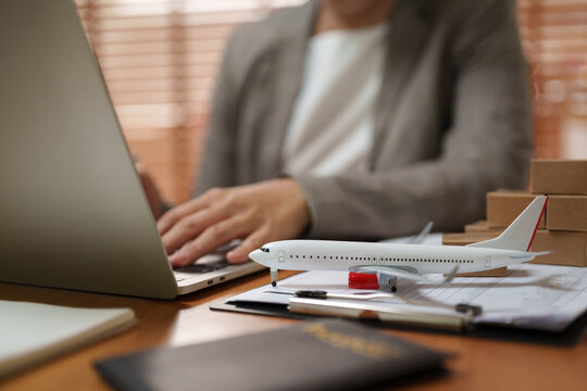 Travel agent working on a laptop with airplane model on desk, representing flight booking, tourism planning, reservations and professional travel agency service.