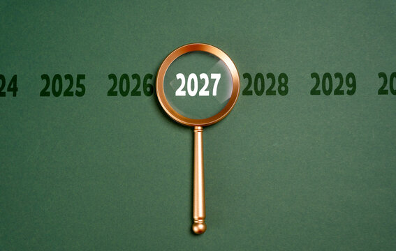 Year 2027 in focus of magnifying glass, future forecast concept. Looking ahead supports business planning, economic analysis and strategic decisions about opportunities, risks