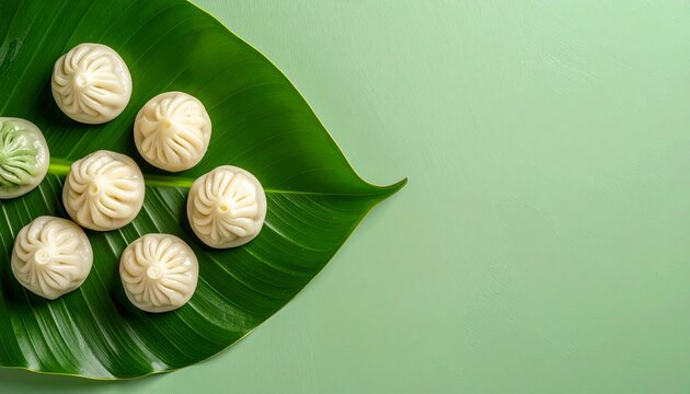 Delicious White Steamed Dumplings Placed on Fresh Green Leaf Background
