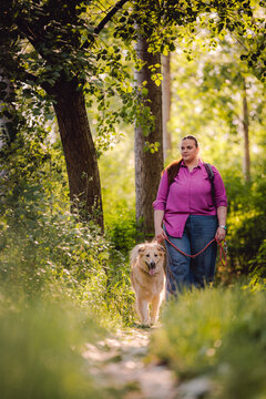 Woman Walking Dog on Forest Trail in Summer Nature Park, Casual Outfit and Backpack