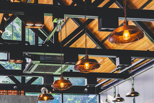 Modern cassette type air conditioner installed on loft ceiling with steel beams and wooden roof. Ceiling-mounted cassette air conditioning unit integrated into modern interior design. HVAC systems.