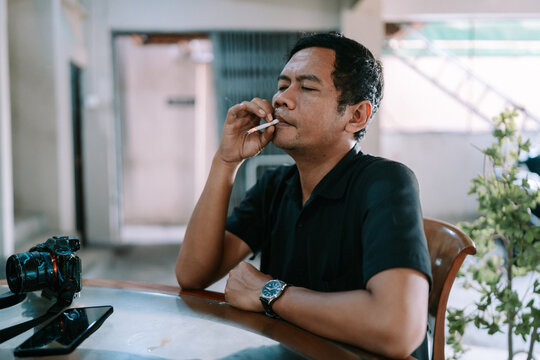 Man Smoking a Cigarette Sitting at a Table