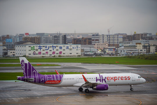 An HK Express Airbus A321 (B-LEL) in the old hkexpress.com livery taxis at the airport with the city skyline behind on July 13, 2019 in Fukuoka, Japan.