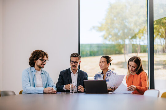 Business Team Meeting in Modern Conference Room Reviewing Documents and Collaborating on Strategy