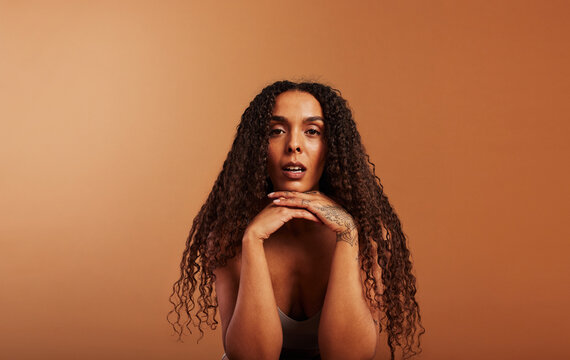 Young black woman sitting in underwear against an orange background