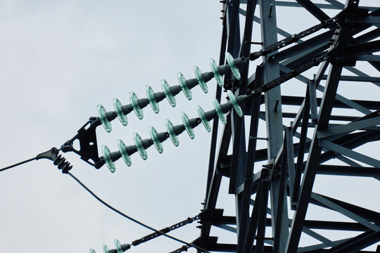 Detailed view of steel lattice pylon body showing multiple glass insulator strings and parallel high voltage wires